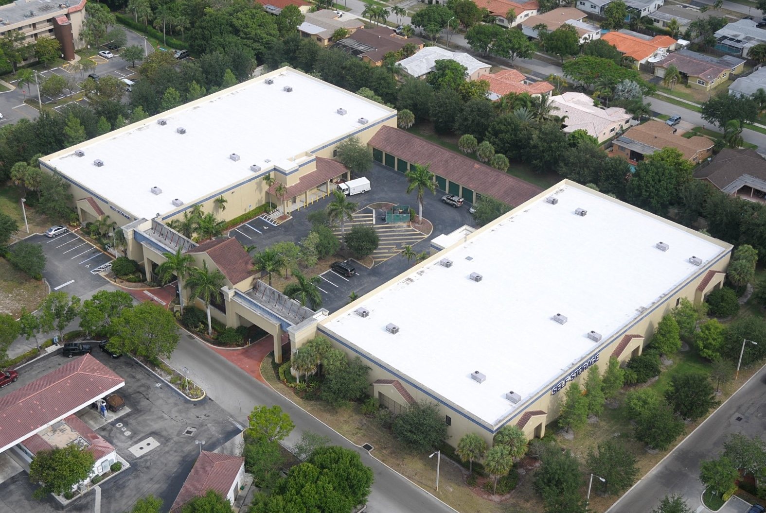 Aerial view of a self-storage facility with a white low-slope commercial roof and tiled entryways