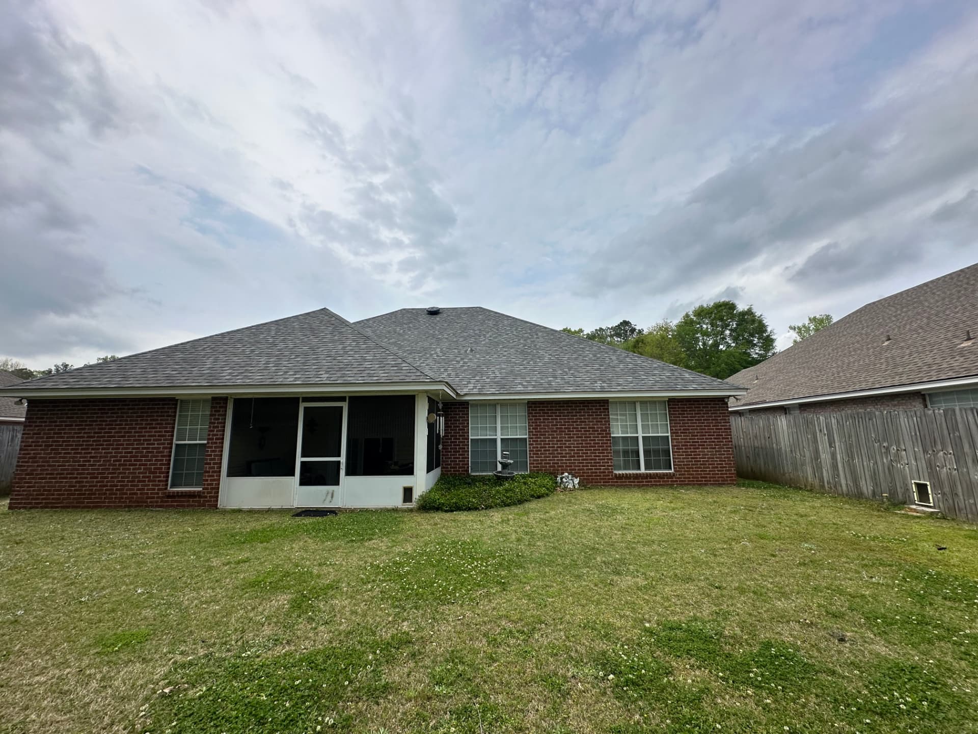 Rear view of a brick home with a completed gray shingle roof